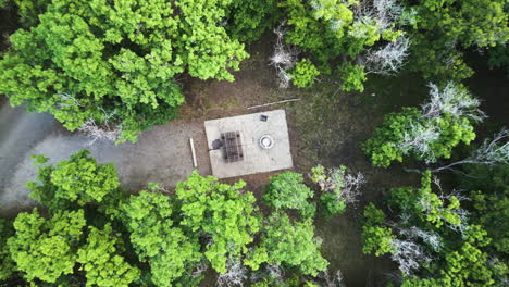 Descending-drone-shot-reveals-campground-setup-amidst-lush-green-trees