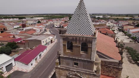 Aerial-view-orbiting-Torremayor-church-bell-tower-with-red-rooftop-and-whitewashed-buildings-in-the-province-of-Badajoz