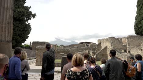 Reiseleiter-Gestikuliert-Den-Besuchern-Den-Einfluss-Des-Vesuvs-Auf-Pompeji