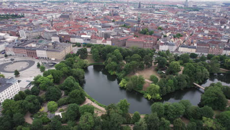 Desde-Arriba,-Se-Puede-Ver-Ørstedsparken-En-El-Centro-De-Copenhague-Con-Sus-Verdes-árboles-Y-Lagos,-Rodeados-Por-Los-Edificios-Circundantes.