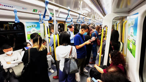 Pendler-In-Einem-überfüllten-MTR-Zug-In-Hongkong,-Der-Nach-Der-Nächtlichen-Arbeit-Nach-Hause-Fährt