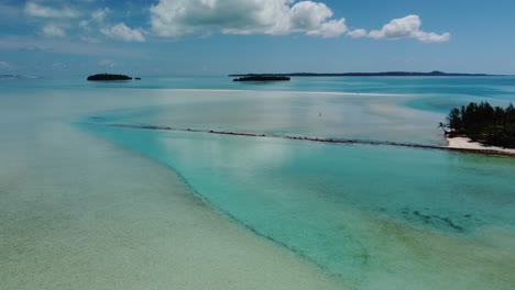 Pristine-tropical-lagoon-with-lone-person-walking-on-sand-flats-in-crystal-clear-water