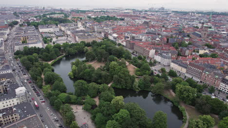 Aerial-view-of-Ørstedsparken-in-central-Copenhagen,-surrounded-by-buildings,-showcasing-lush-green-trees-and-lakes