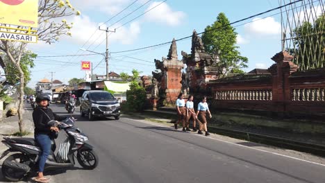 Tráfico-Callejero-Panorámico-En-Ubud-Bali-Indonesia-A-La-Luz-Del-Día,-Templos-De-Motocicletas-Y-Gente-Caminando,-Estilo-De-Vida-Diario