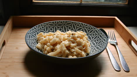 Focus-Pull-to-Macaroni-Cheese-Meal-with-Spoon-and-Fork-on-Wooden-Tray