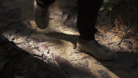 Close-up-dolly,-footsteps-walking-in-the-jungle-with-shadow-casted,-Adidas-kampung