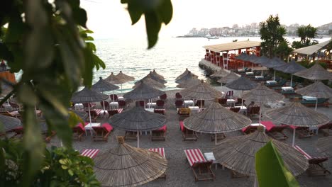 View-of-straw-umbrellas-and-sunbeds-on-the-beach-by-the-sea-in-Saranda
