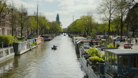 Peaceful-Amsterdam-Canal-in-spring-with-boots-cruising-slowly-on-it