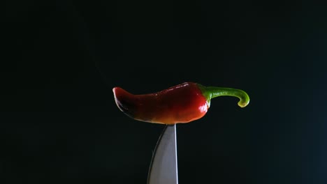 A-smoking-jalapeno-on-the-point-of-a-knife-with-a-dark-background