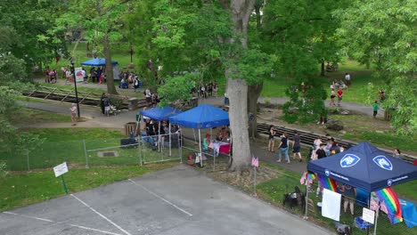 Drone-view-of-several-people-gathering-in-a-park-for-a-pride-festival-with-tents-and-vendors