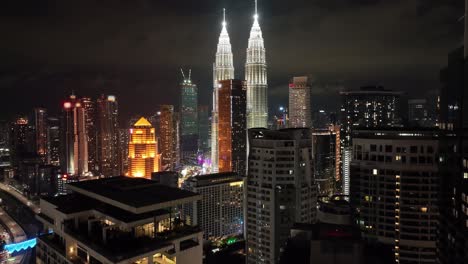 Aerial-night-reveal-establishing-shot-of-the-Petronas-Towers-in-Kuala-Lumpur,-Malaysia