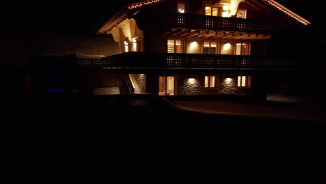 Beautiful-dolly-out-of-chalet-with-hot-tub-with-burning-lamps-at-night