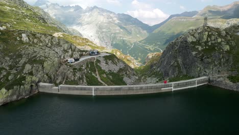 Scenic-aerial-view-of-Totensee-lake-and-dam-of-Grimsel-Pass-in-summer-season-with-mountain-range-in-background,-Switzerland