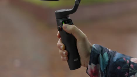 Female-hand-holds-DJI-Osmo-Mobile-6-gimbal-and-press-button-with-thumb-finger