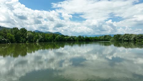 Aerial-Above-Lake-Žovnek-Slow-Motion-Water-Reflection-Landscape,-Green-Forest-and-Blue-Skyline,-Drone-Shot-in-Slovenia,-Braslovče