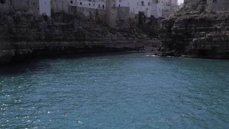 Camera-moving-upwards-from-sea-waves-towards-a-scenic-view-of-Polignano-a-Mare