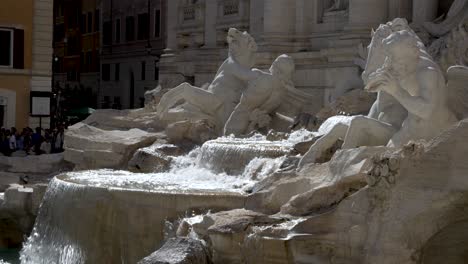 Eine-Nahaufnahme-In-Zeitlupe-Des-Kaskadierenden-Wassers-Des-Trevi-Brunnens-Und-Der-Umliegenden-Skulpturen-An-Einem-Sonnigen-Tag,-Rom,-Italien