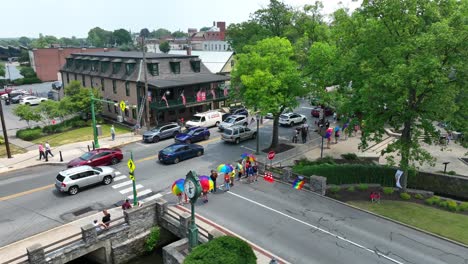 Drone-view-of-people-with-pride-umbrellas-gathering-near-a-park-for-a-pride-festival-on-a-summer-day