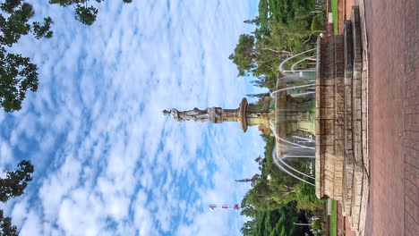 Vertical-Timelapse-of-people-at-the-fountain-of-Coconut-Tree-Square,-in-sunny-Noumea