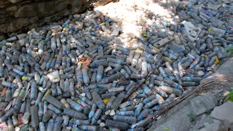 Close-up-of-thousands-of-plastic-water-bottles-and-rubbish-polluting-a-stream-in-city-centre-causing-environmental-disaster,-Southeast-Asia