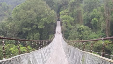 Two-people-in-the-distance-walk-over-the-Situ-Gunung-Suspension-Bridge-in-Sukabumi,-West-Java,-Indonesia