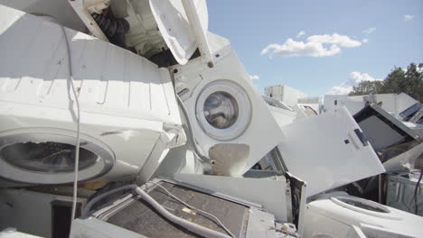 White-discarded-appliances-dumped-onto-pile-at-disposal-centre,-slider