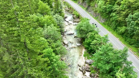 Aerial-Drone-Above-Road-with-Driving-Car-in-Green-Forest-Mountains-Scenic-Logar-Valley-River-Slovenia-Travel-and-Tourism