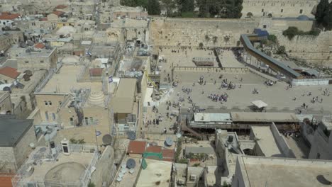 Aerial-view-of-People-at-Jerusalem-Western-wall,-a-known-worship-place-for-Jewish-people-and-the-Dome-of-the-rock-in-the-background