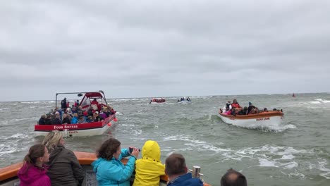 Several-boats-full-of-people-on-a-seal-tours-go-up-and-down-the-coast-at-Blakeney-Point,-north-Norfolk