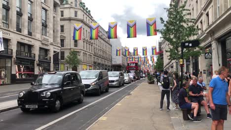 People-walk-under-some-LGBTQ-flags-that-fly-along-Oxford-Street,-London