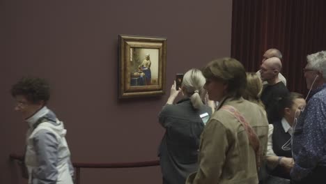 Group-at-Amsterdam-museum-admiring-Vermeer's-"The-Milkmaid"-art-exhibition-indoors