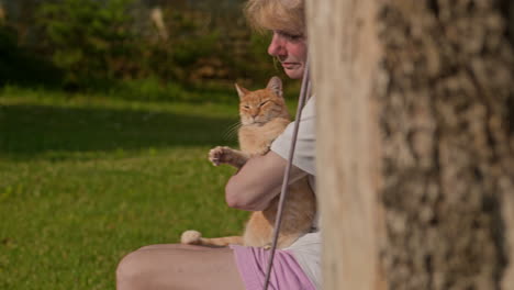 Woman-on-tree-swing-strokes-her-adorable-ginger-pussy-cat,-slide-reveal
