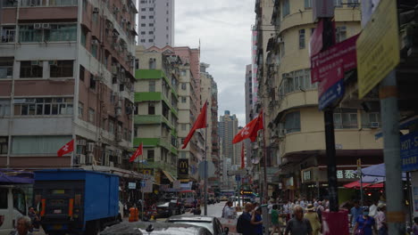 Belebte-Straße-Mit-Markt-Und-Bussen-Und-Menschen,-Die-Unter-Den-Flaggen-Chinas-Und-Hongkongs-Laufen