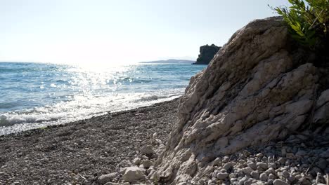 Beach-in-Greece,-rocky-cliff-against-the-backdrop-of-waves-of-the-Ionian-Sea