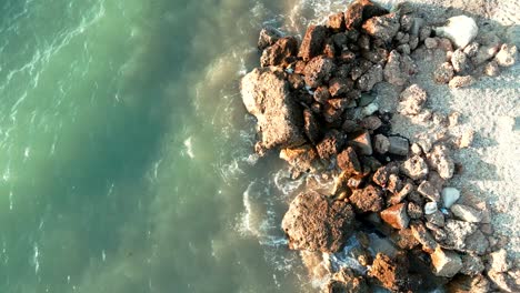 Albania,-foamy-waves-crashing-against-rocks-on-the-beach---aerial-view-from-a-drone