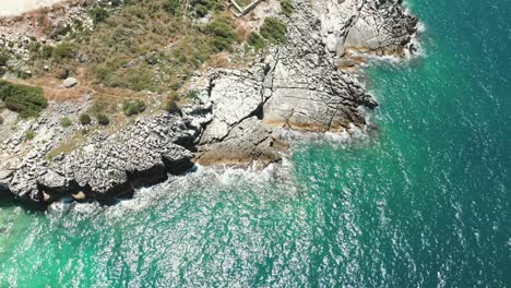 Albania,-blue-waters-of-the-Ionian-Sea-and-foamy-waves-crashing-against-the-rocky-shore