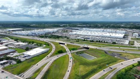 Wide-shot-of-highway-interchange-with-vehicle-manufacturing-plant-in-distance