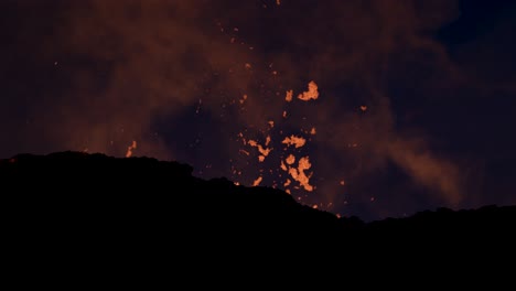 Hot-glowing-lava-bursting-violently-from-volcano-crater-at-night