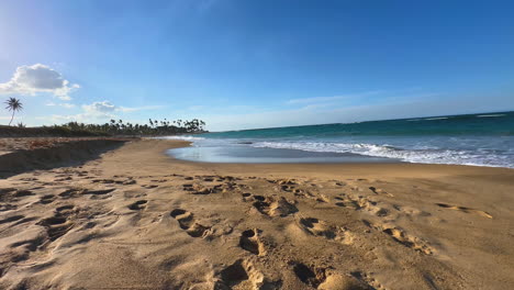 Meereswellen-Rollen-Auf-Einen-Sandstrand-Mit-Palmen-Am-Fernen-Horizont-In-Punta-Cana,-Dominikanische-Republik