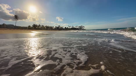 sunset-at-the-beach-in-Punta-Cana,-Dominican-Island-of-Hispaniola-with-palm-trees-on-the-background-and-rolling-waves-on-a-sandy-beach