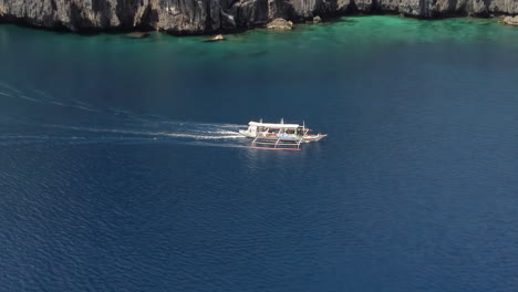 Filmische-Luftaufnahmen-Eines-Auslegerbootes,-Das-An-Den-Klippen-In-Palawan,-Philippinen,-Asien-Vorbeifährt,-Drohne