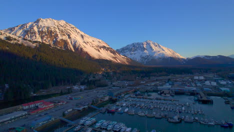 Scenic-drone-view-flying-away-from-Seward-Boat-Harbor-and-mountains-at-sunrise-in-Seward-Alaska