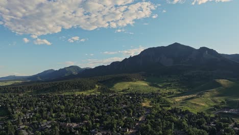 Aerial-over-the-forested-hills-of-Boulder-with-the-Flatirons-mountain-peaks-in-the-background,-Colorado,-USA