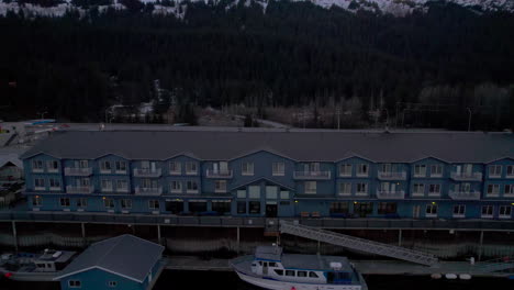 Aerial-drone-view-right-to-left-of-Harbor-360-Hotel-in-Seward-Alaska-with-mountains-at-sunset