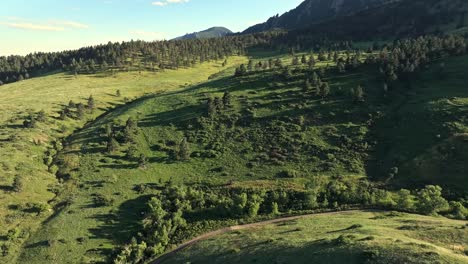 Luftaufnahme-über-Den-Bewaldeten-Hügeln-Von-Boulder-Mit-Den-Flatirons-Berggipfeln-Im-Hintergrund,-Colorado,-USA