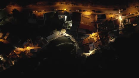 Mesmerizing-overhead-view-of-a-charming-coastal-fisherman-village-at-night,-adorned-with-beautiful-street-lights
