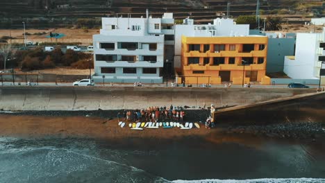 AERIAL-SLOWMO:-Group-of-surfers-on-the-beach-in-a-funeral's-ceremony-in-Canary-Islands