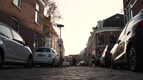 Amsterdam,-Países-Bajos,-Ciudad,-Calle-Adoquinada,-Con,-Automóviles,-Y,-Edificios-De-Departamentos,-En,-Plano-De-Fondo,-En,-Ocaso
