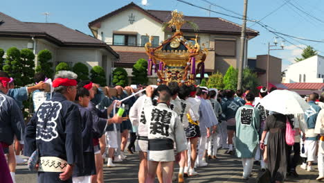 Japanese-people-carrying-omikoshi-portable-shrine-on-hot-day-at-small-local-summer-matsuri-festival
