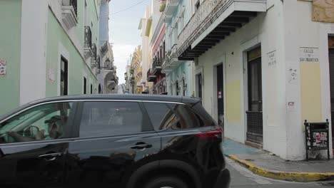 Old-San-Juan,-Puerto-Rico-historical-town-street-view-with-pedestrians-and-light-traffic---Whip-Panning